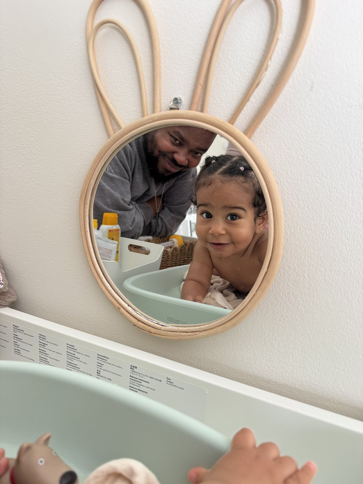 Bebé e pai refletidos no espelho da sala de mudinha da Bloom